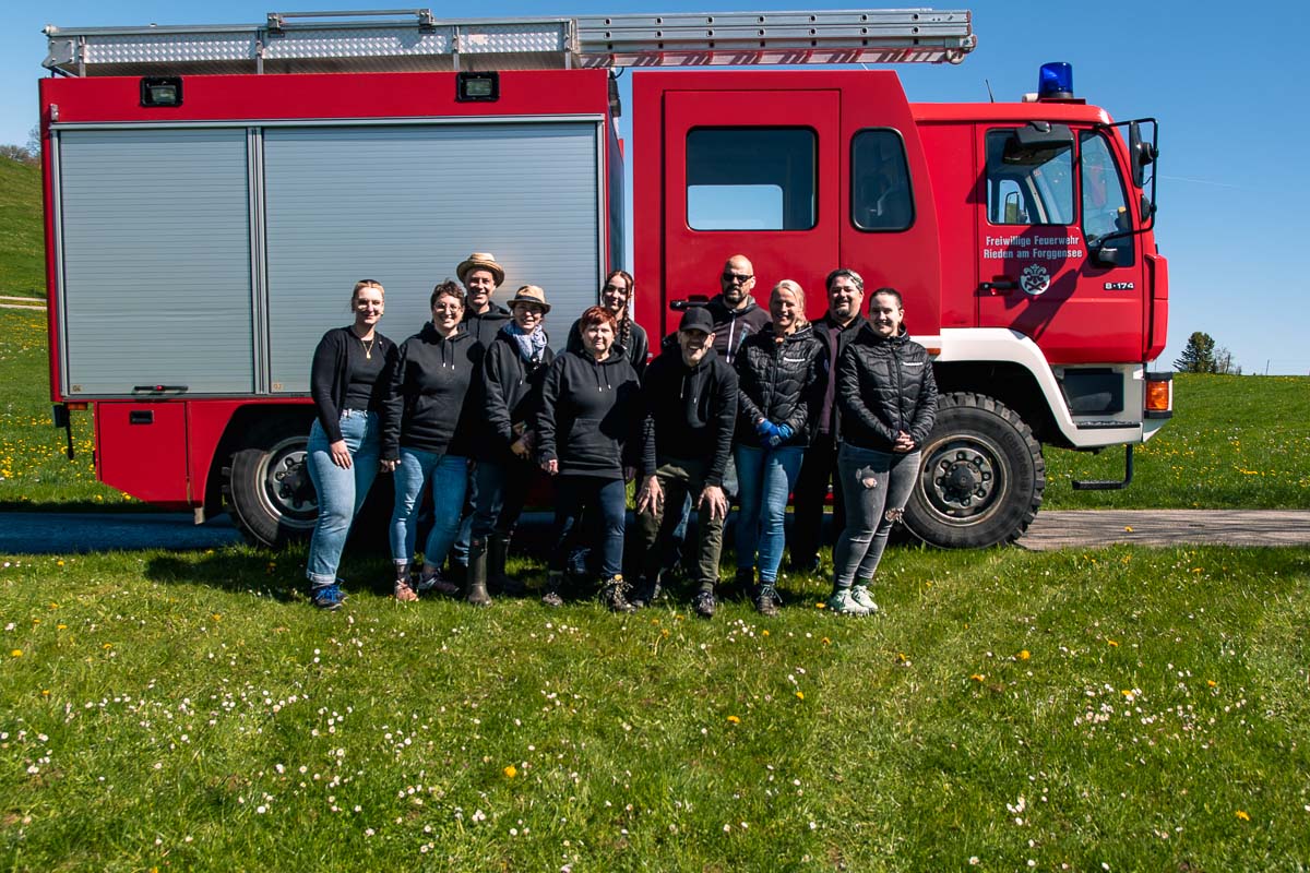 Das Team von Bauernhofurlaub.de steht gemeinsam vor einem roten Feuerwehrfahrzeug auf einer Wiese.